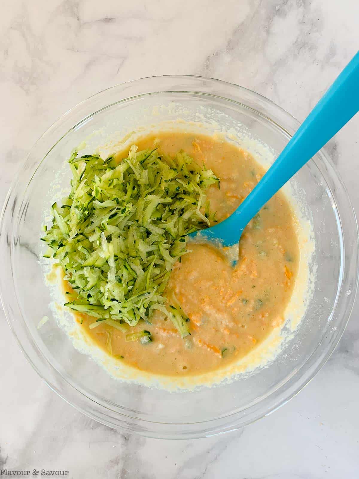 Adding shredded zucchini to zucchini cheese muffin batter.