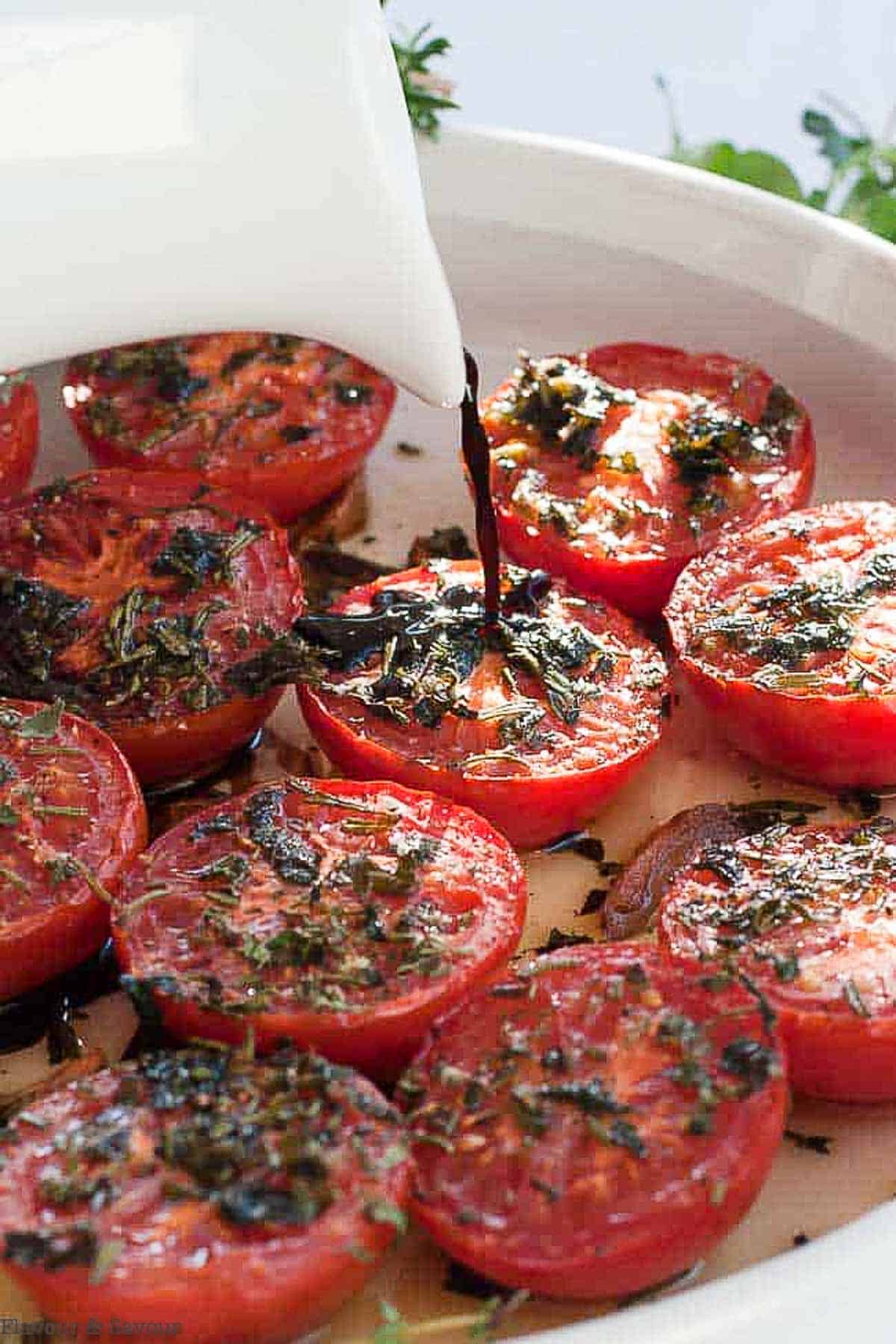 Drizzling balsamic vinegar on broiled Italian tomatoes with garlic and herbs