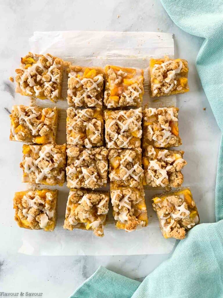 Sliced peach crumble bars with frosting.