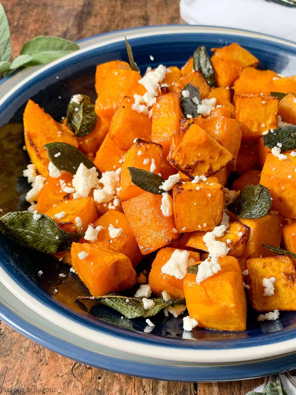 cubes of air fried butternut squash with feta cheese crumbles and toasted sage leaves