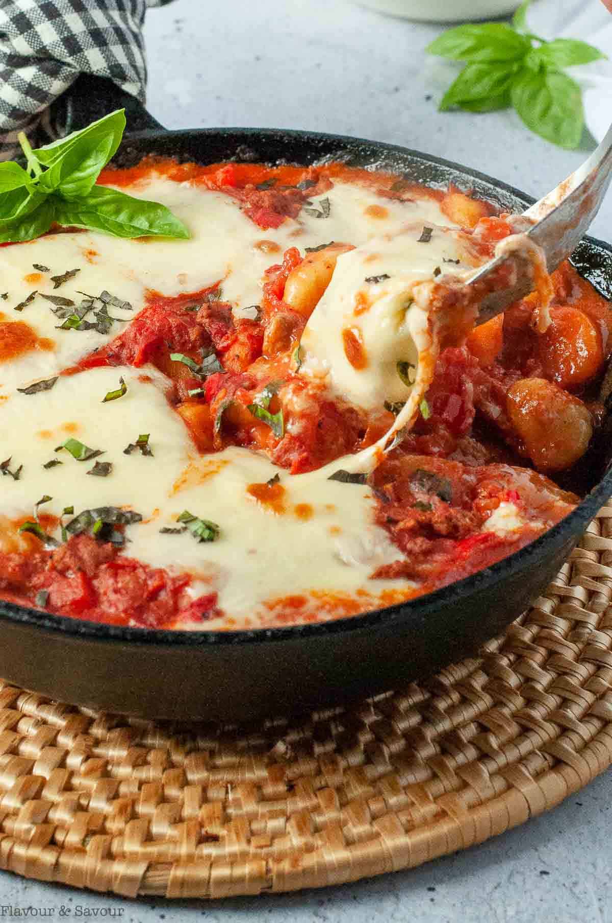 Cheese and tomato gnocchi casserole baked in a cast iron skillet.