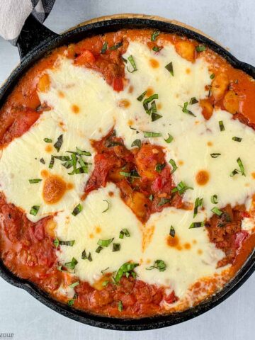 a cast iron skillet with cheesy tomato gnocchi bake