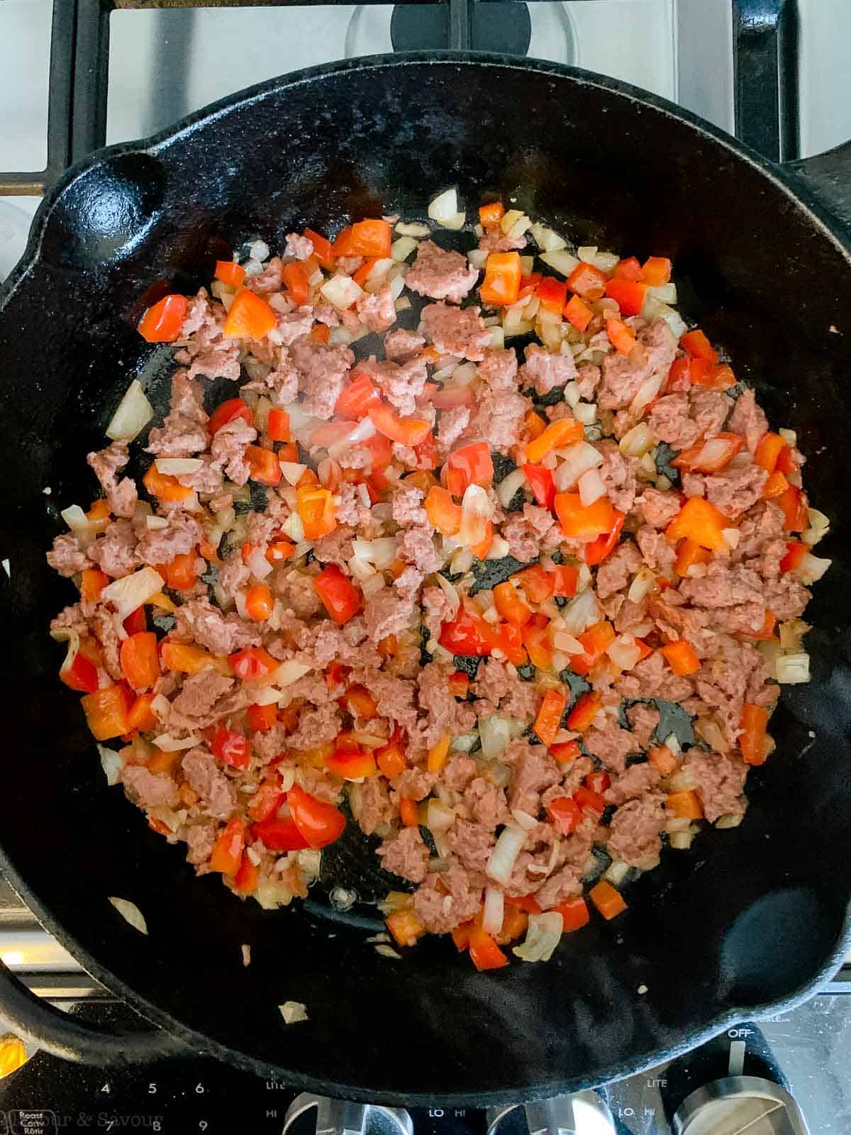 onions, peppers, garlic and plant-based meat in a skillet.