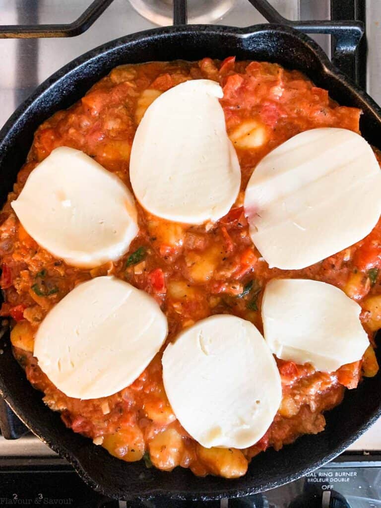 Mozzarella slices on top of tomato gnocchi casserole.