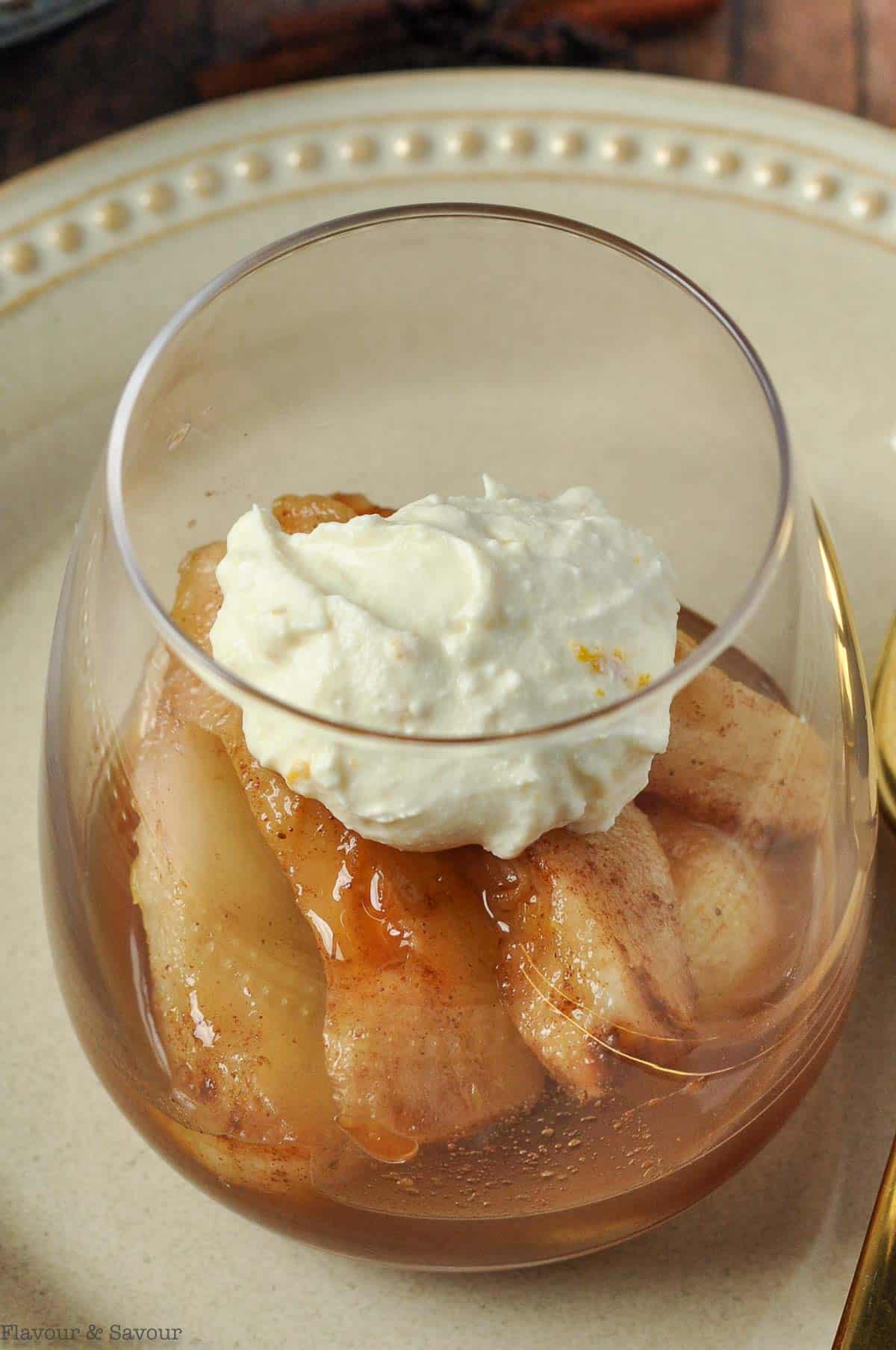 Poached cinnamon orange pears with mascarpone in a dessert glass.