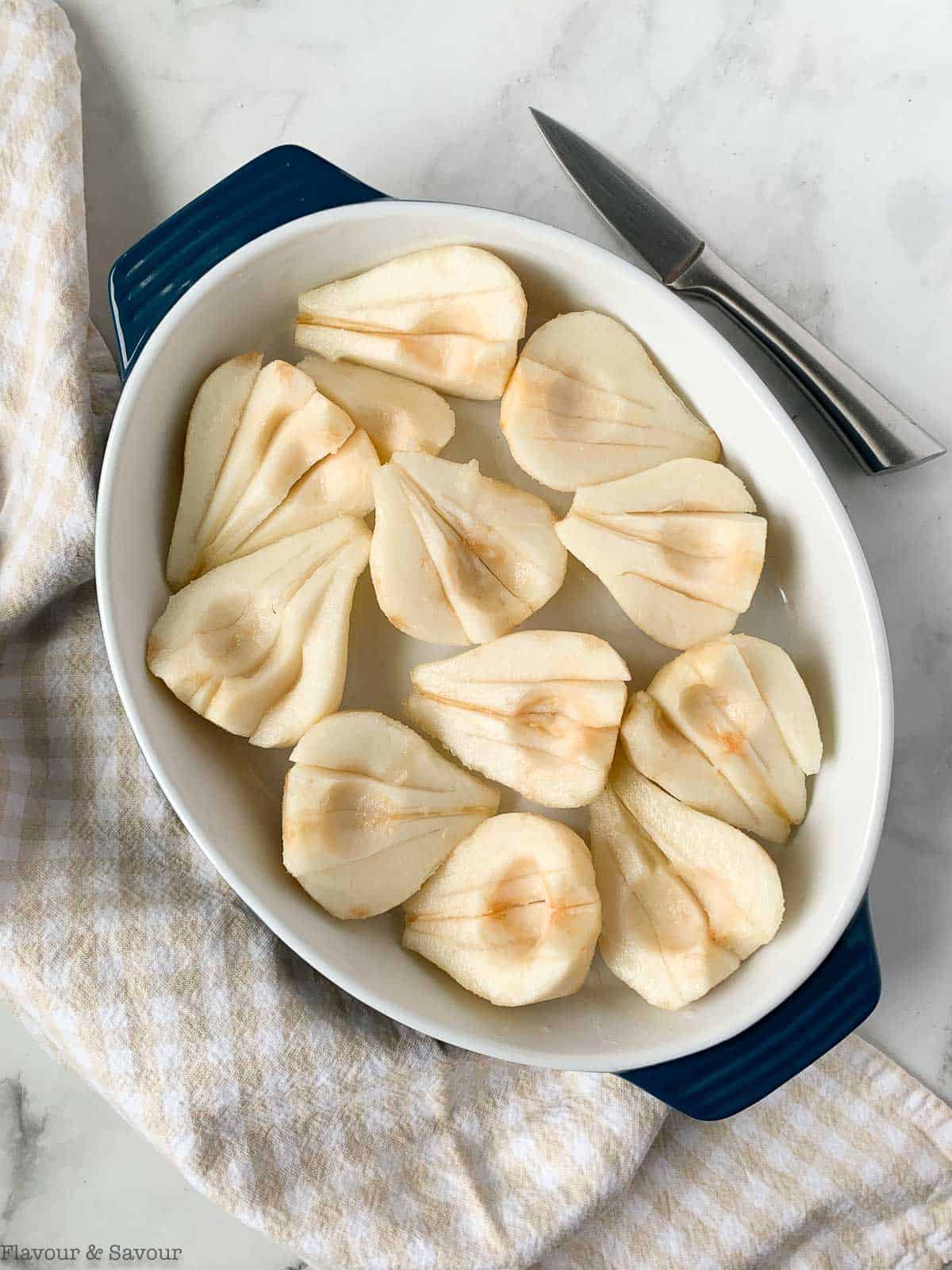 Peeled pear halves in a baking dish.