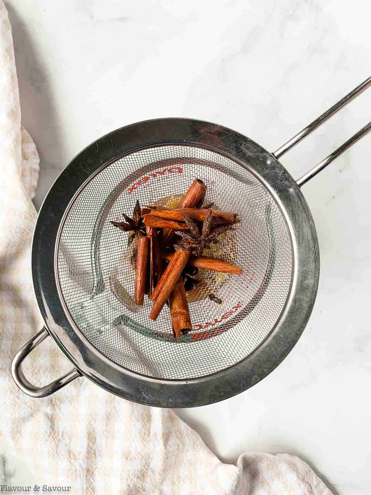 Spices in a sieve after straining pear poaching liquid.