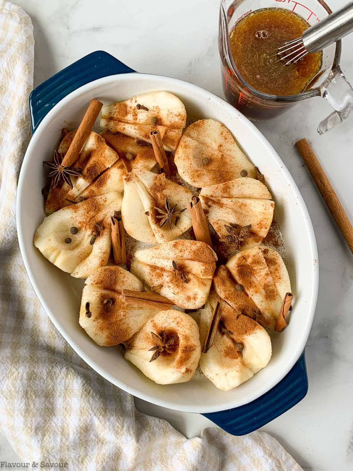 Cinnamon orange pears in a baking dish sprinkled with spices.