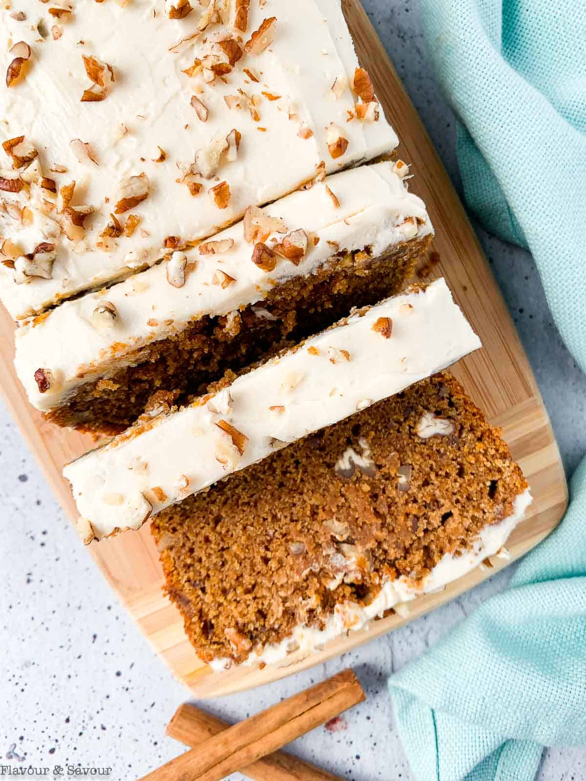 Overhead view of slices of pumpkin spice bread frosted with cream cheese frosting and chopped pecans.