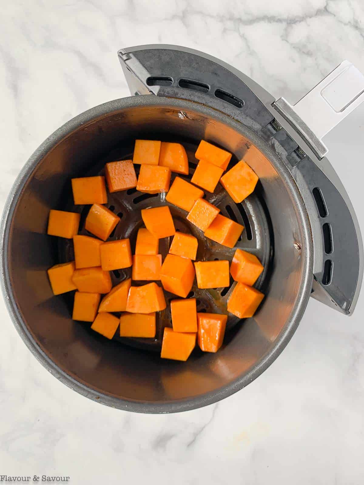 butternut squash cubes in an air fryer basket