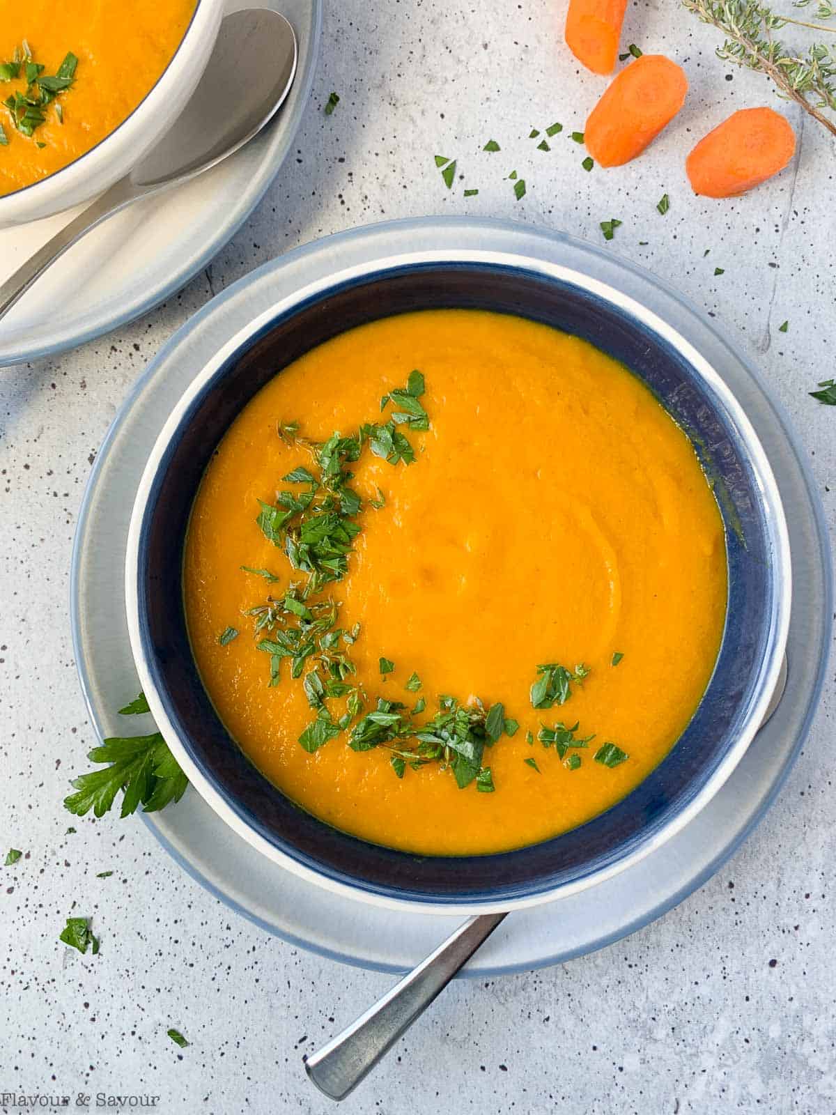 a bowl of carrot ginger soup garnished with parsley and thyme