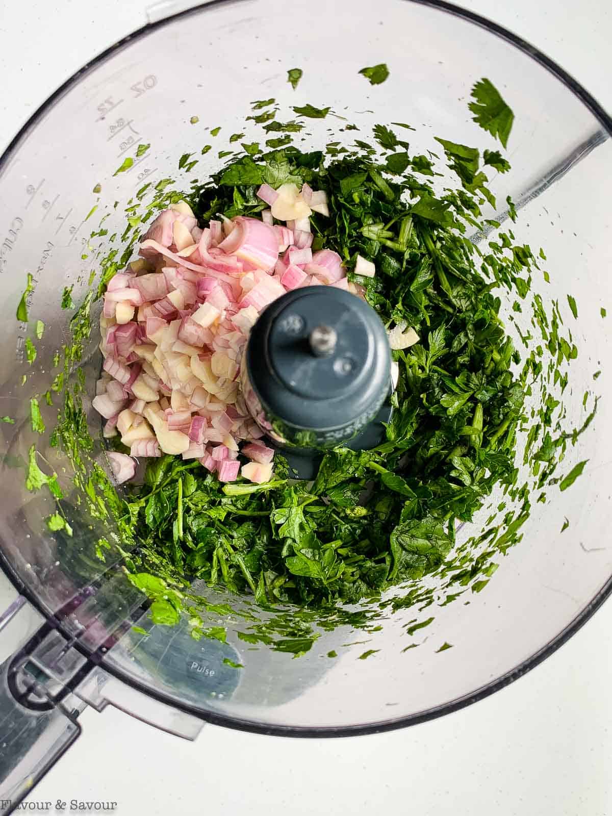 Chimichurri sauce ingredients in a food processor bowl.
