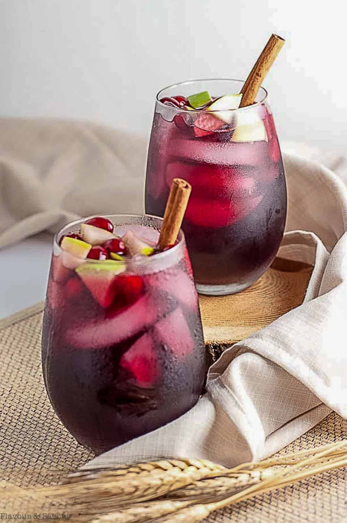 Two glasses of cranberry apple cider sangria with cinnamon sticks.