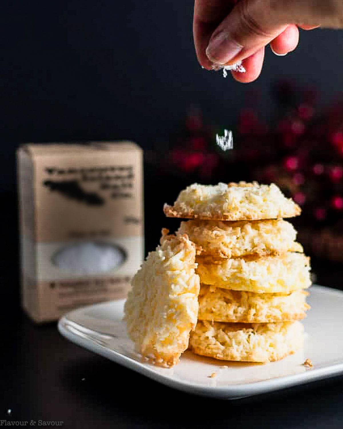 Sprinkling salt on a stack of coconut cookies.