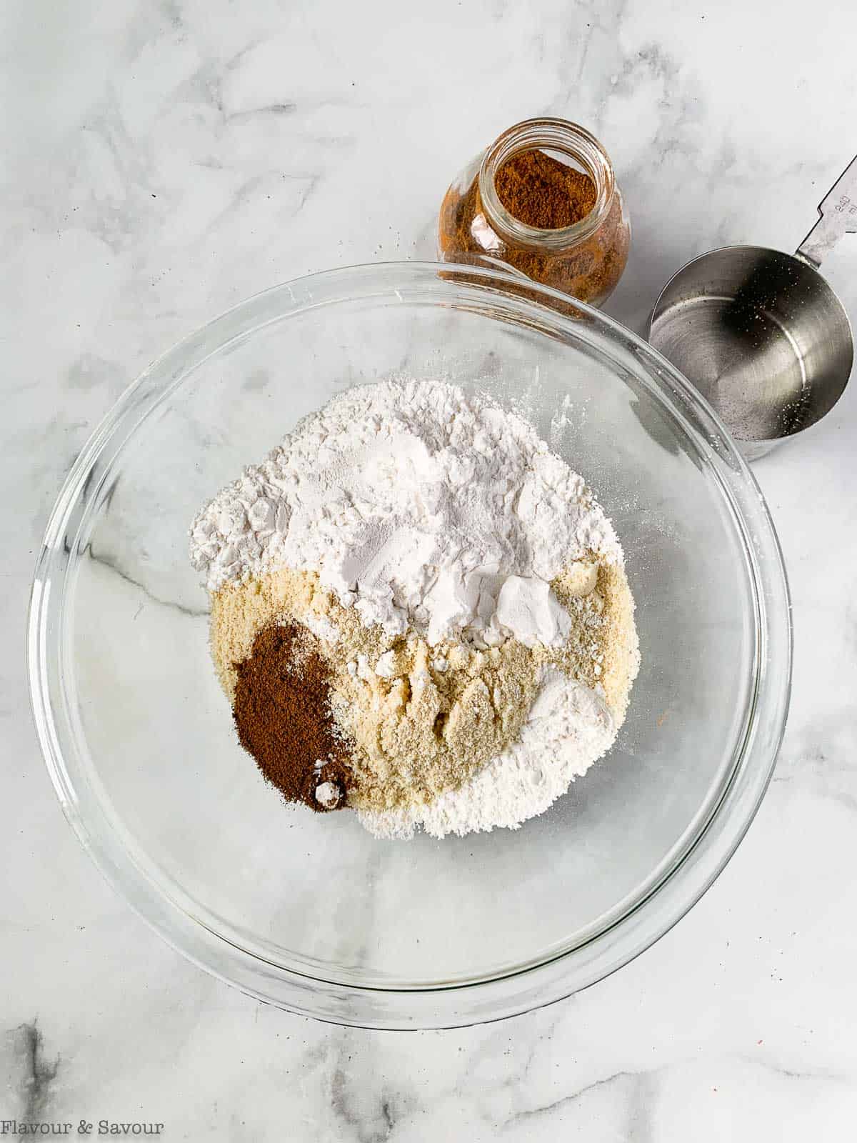 Dry ingredients for pumpkin spice bread in a glass bowl.