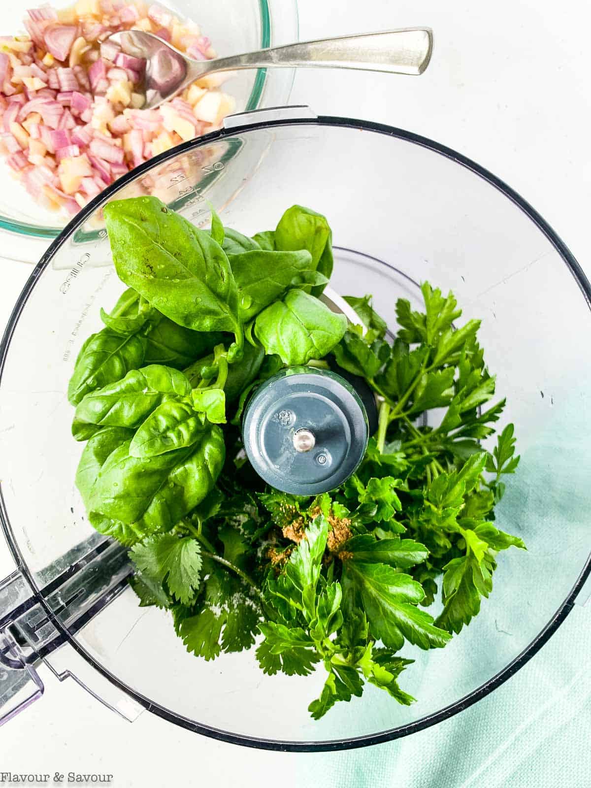 Fresh herbs in a food processor bowl.