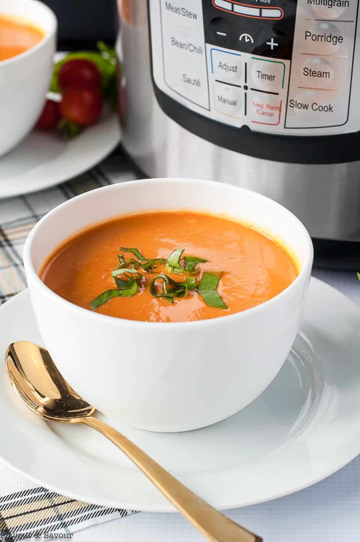 a bowl of creamy tomato soup beside an Instant Pot