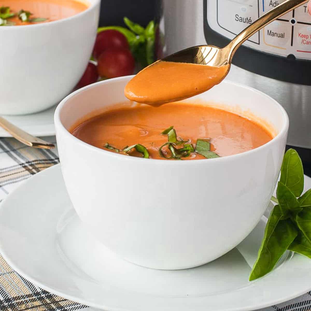 a bowl of instant pot tomato soup with cream garnished with basil