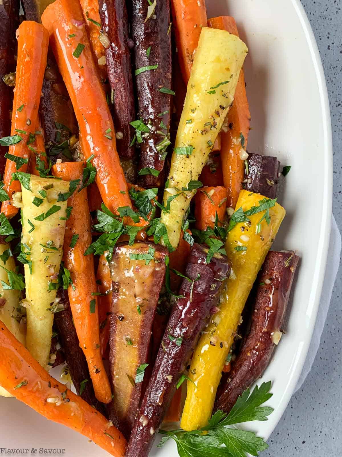 rainbow carrots in a serving bowl with honey-mustard glaze and chopped parsley