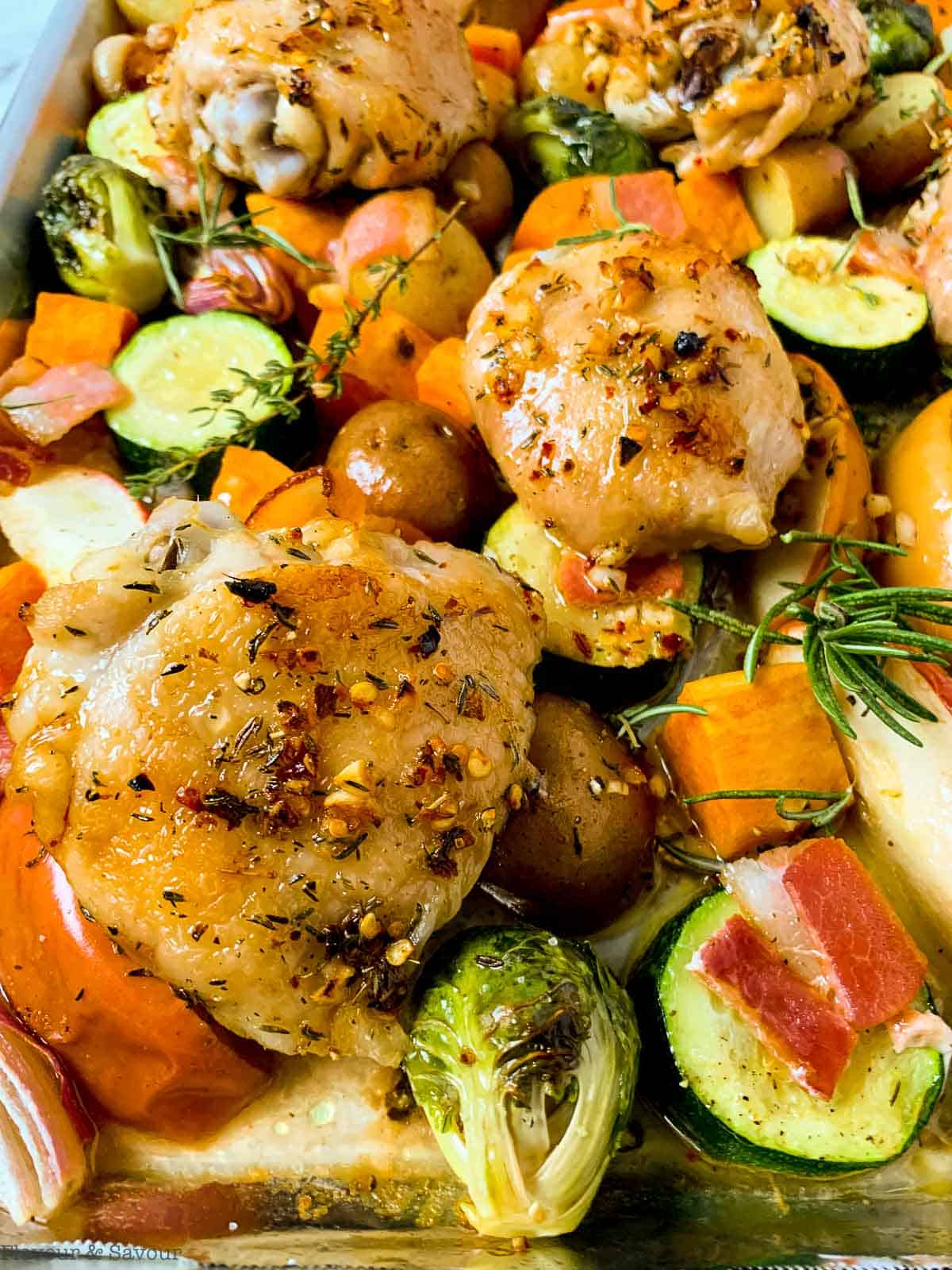 Roasted chicken thighs and fall vegetables on a sheet pan.