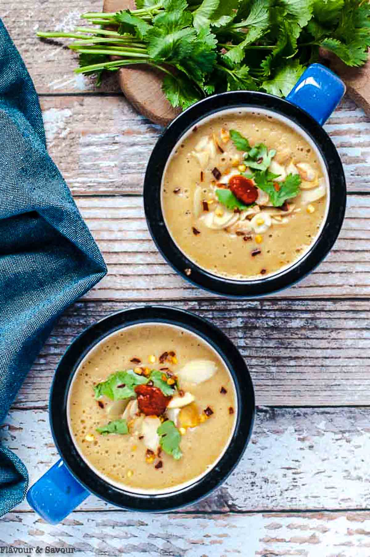 Overhead view of two mugs of Moroccan harissa cauliflower soup.