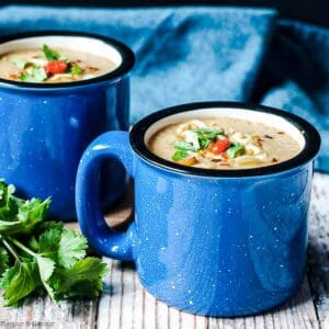 Close up view of two blue soup mugs with Moroccan Harissa Cauliflower Soup.