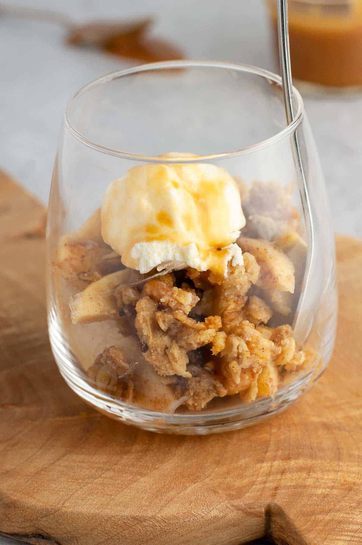 apple crisp with caramel sauce in a dessert glass with a spoon