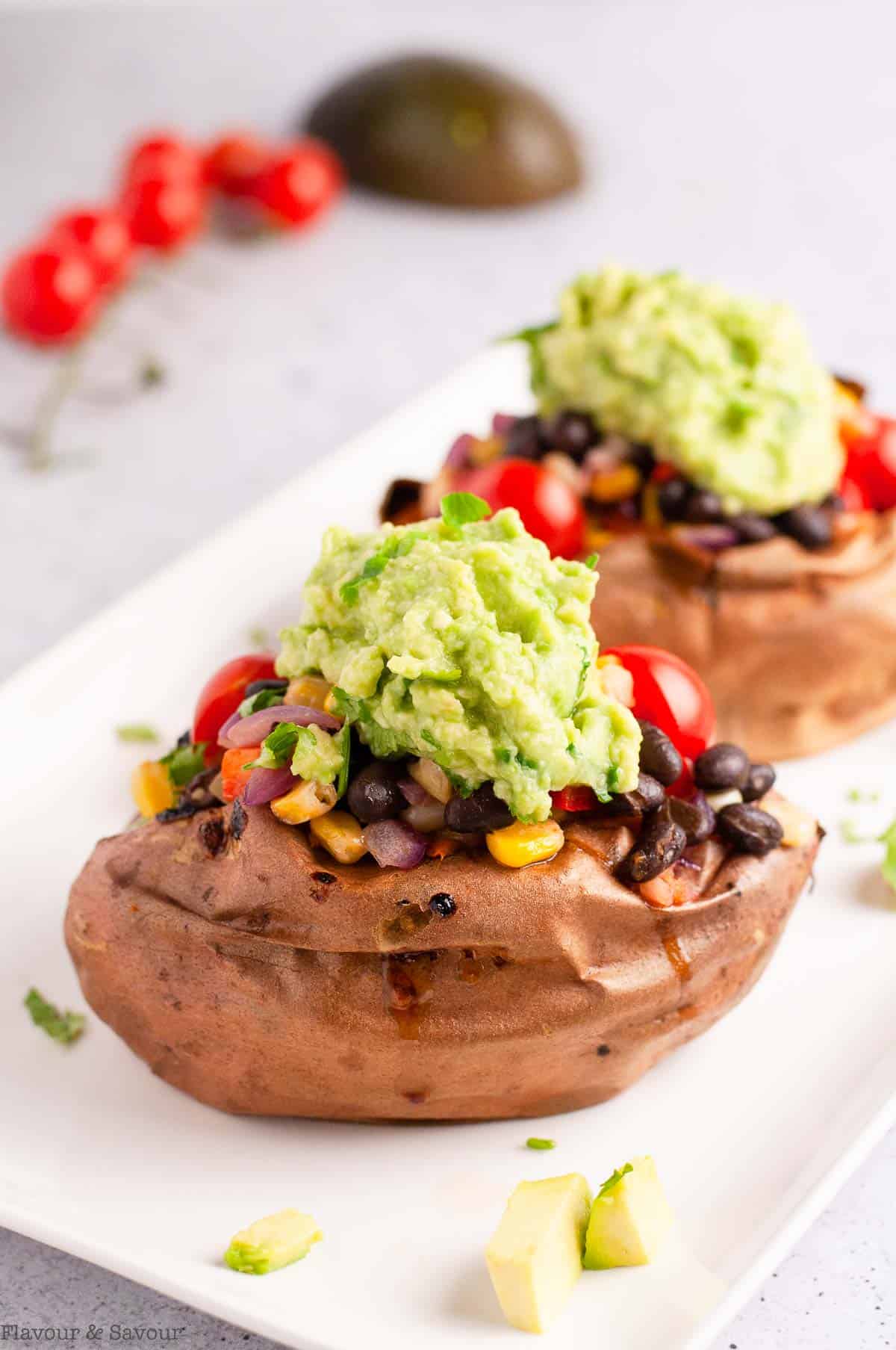 Two sweet potatoes stuffed with black bean mixture and topped with guacamole.
