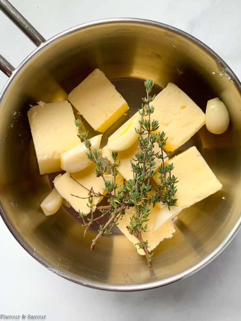 Butter, garlic and thyme in a saucepan for Instant Pot Mashed Potatoes.