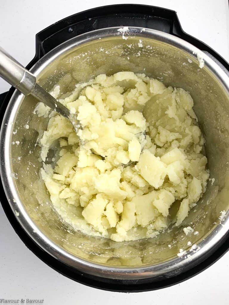 Mashing potatoes in an Instant Pot bowl.