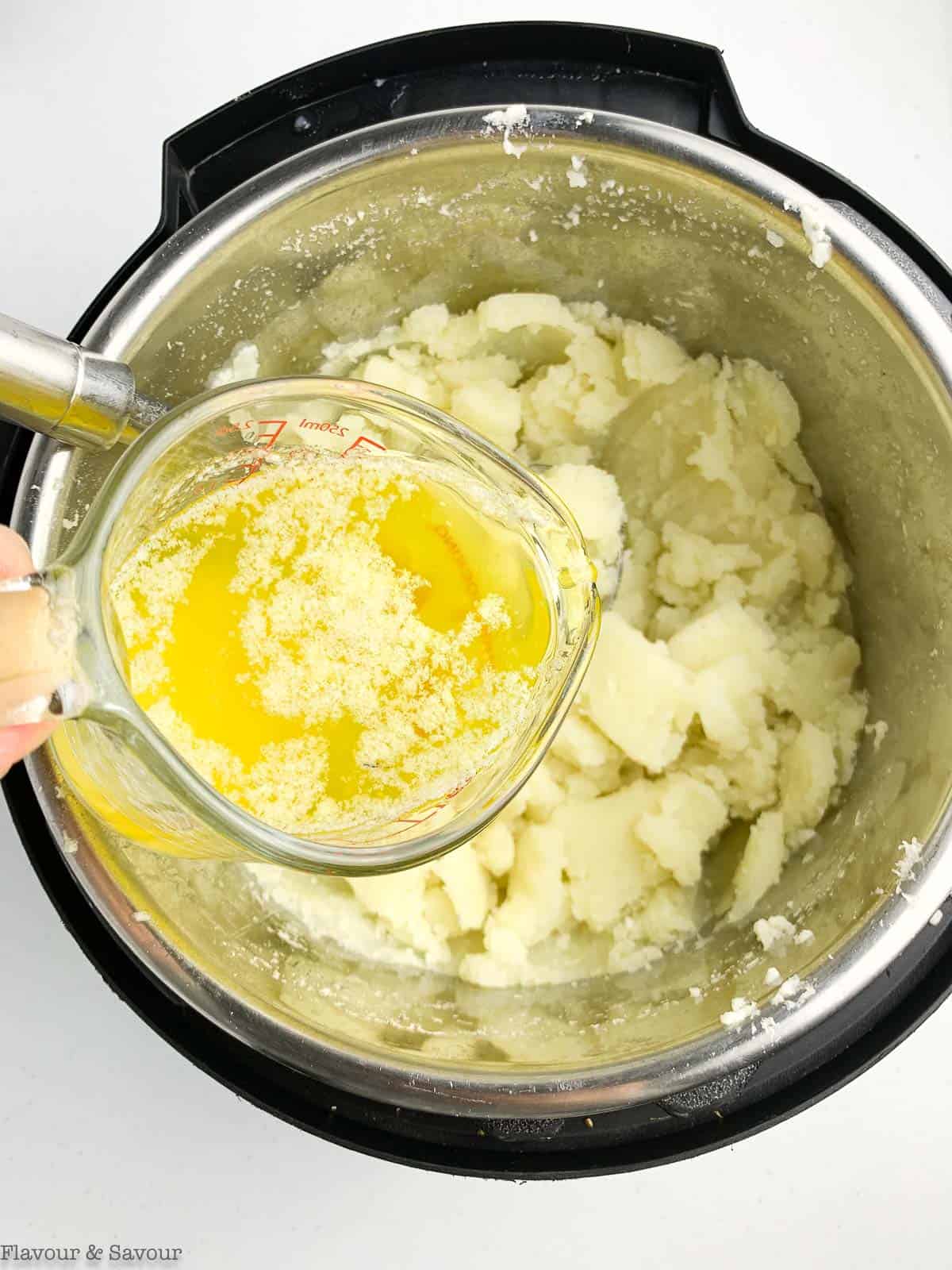 Adding garlic butter to mashed potatoes for vegetarian shepherd's pie.
