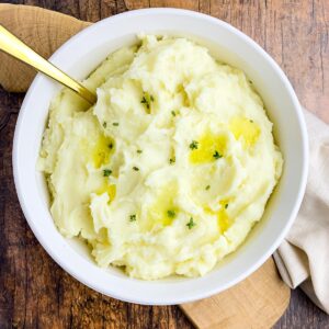 a bowl of instant pot garlic mashed potatoes with butter and fresh thyme