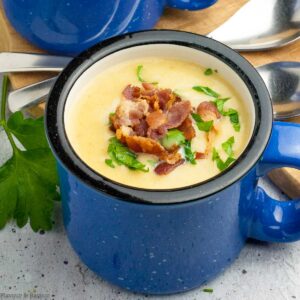 a blue soup mug with instant pot potato leek soup with bacon garnish