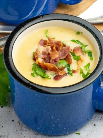 a blue soup mug with instant pot potato leek soup with bacon garnish