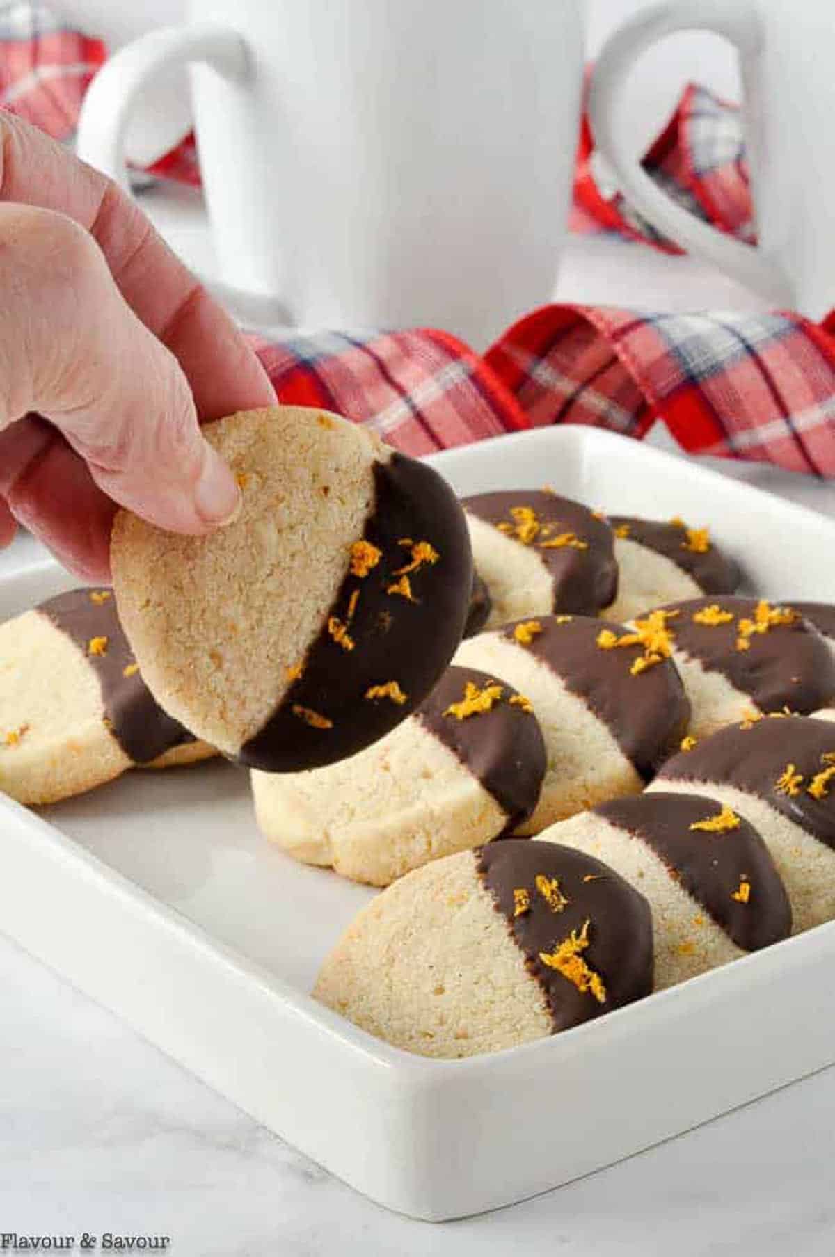 A hand selecting an orange cardamom almond flour cookie.