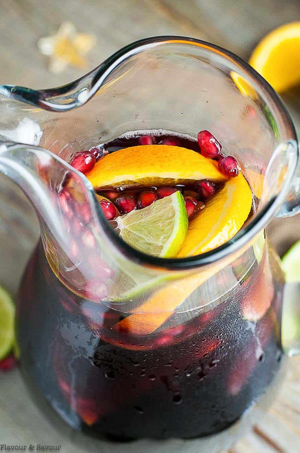 overhead view of a pitcher of pomegranate sangria with oranges, lemons and pomegranate arils
