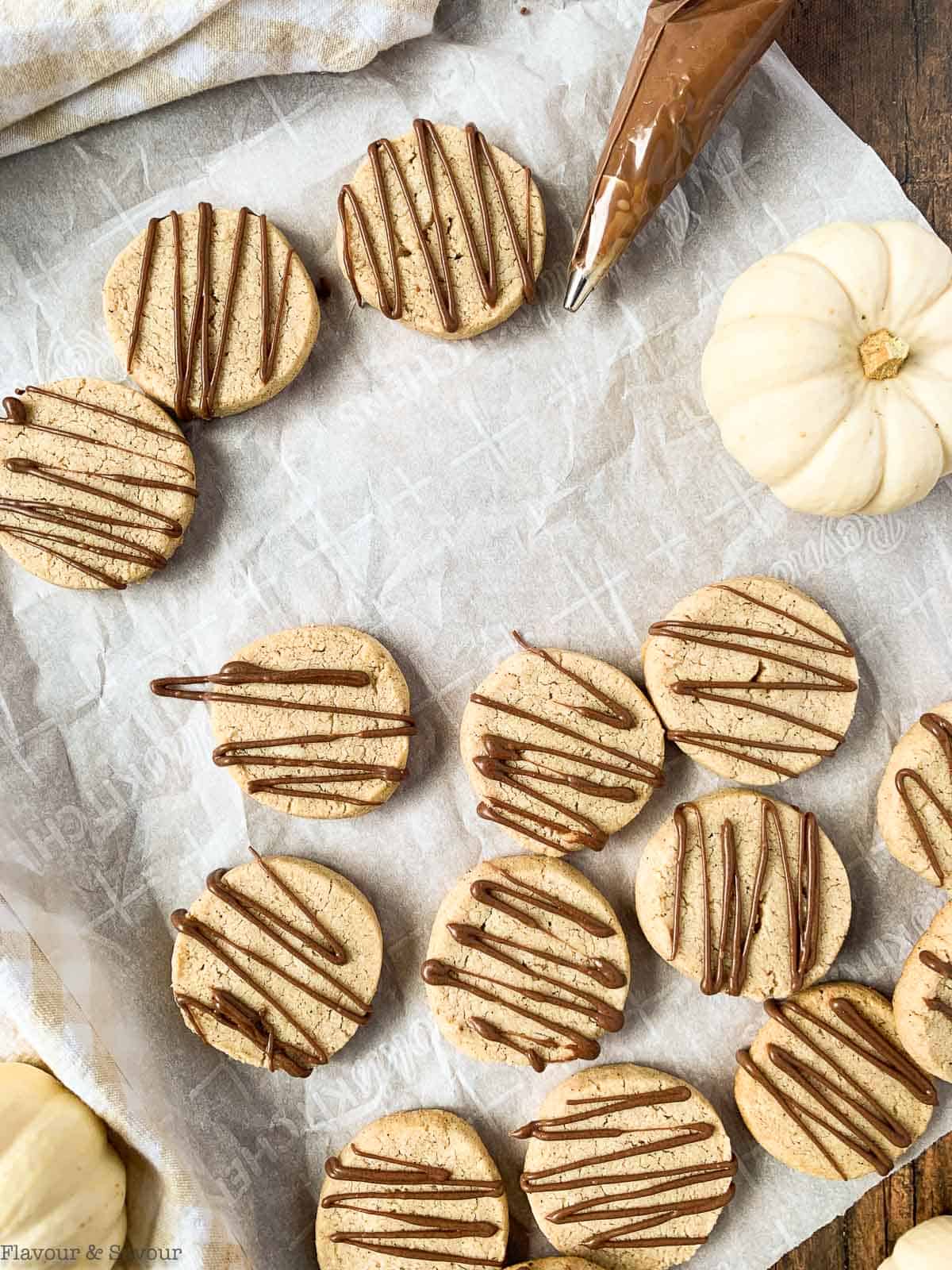 Gluten-free pumpkin spice cookies with chocolate drizzle and a piping bag filled with chocolate