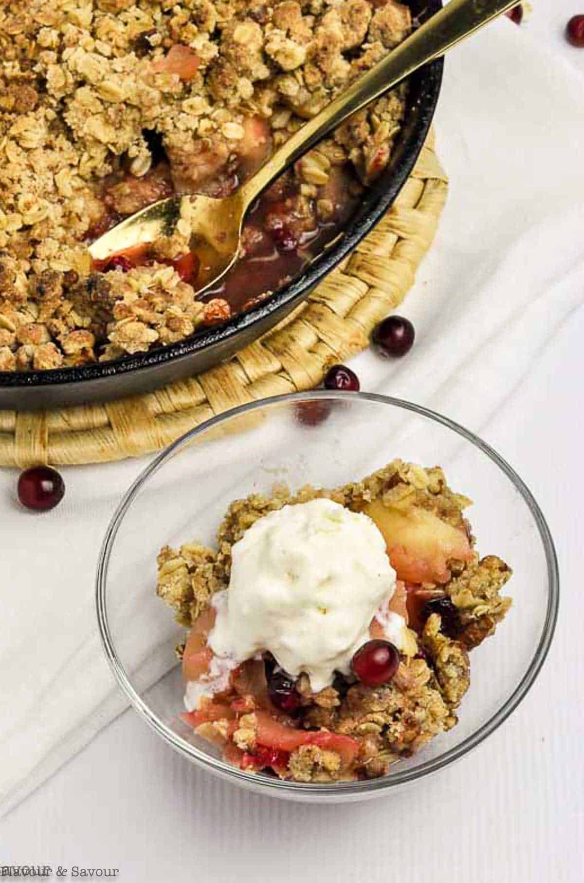 Skillet Cranberry Apple Crisp in a bowl beside a cast iron pan