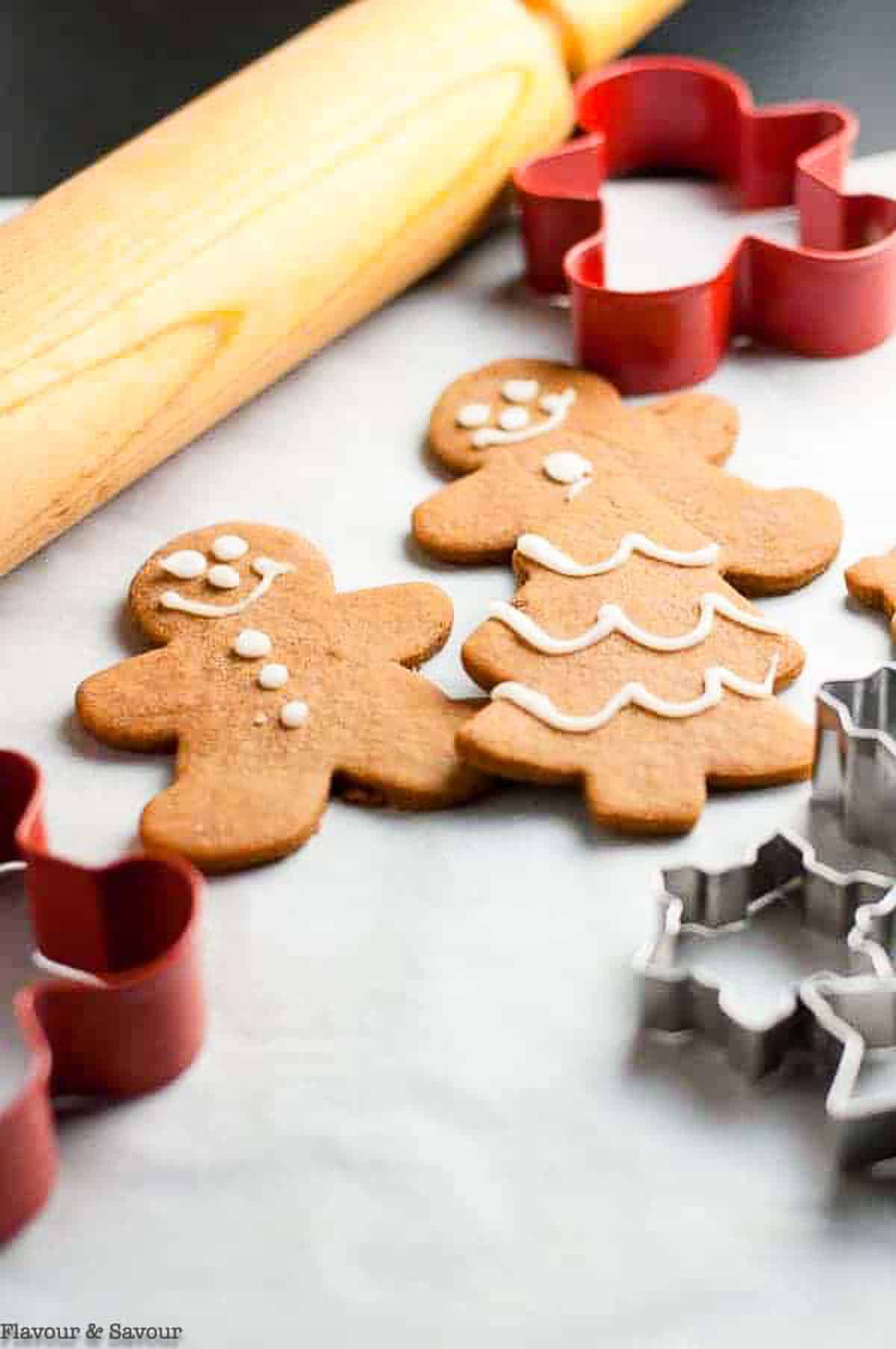 gingerbread people cut-out cookies beside cookie cutters and a rolling pin