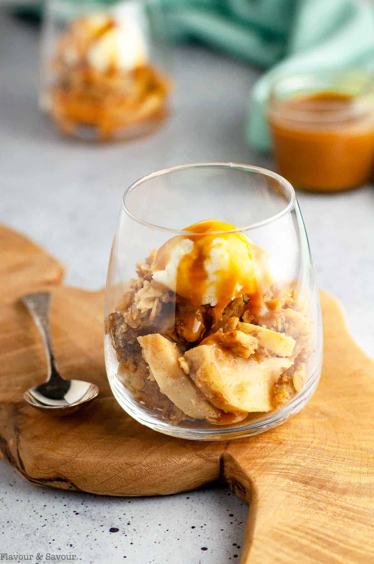 a dessert glass with apple crisp, ice cream and salted bourbon caramel sauce