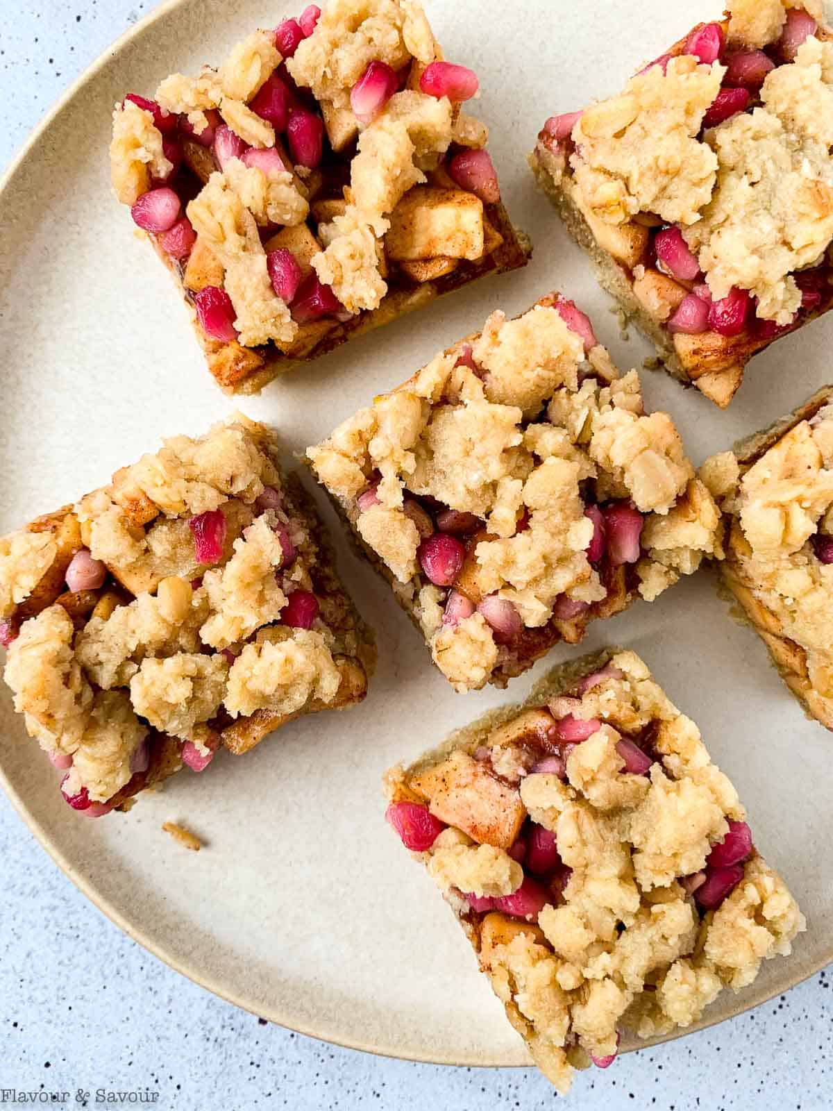 close up view of apple pomegranate crumble bars on a round plate