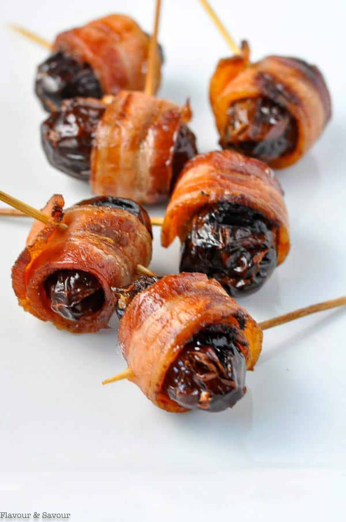 close up view of bacon-wrapped stuffed dates on toothpicks