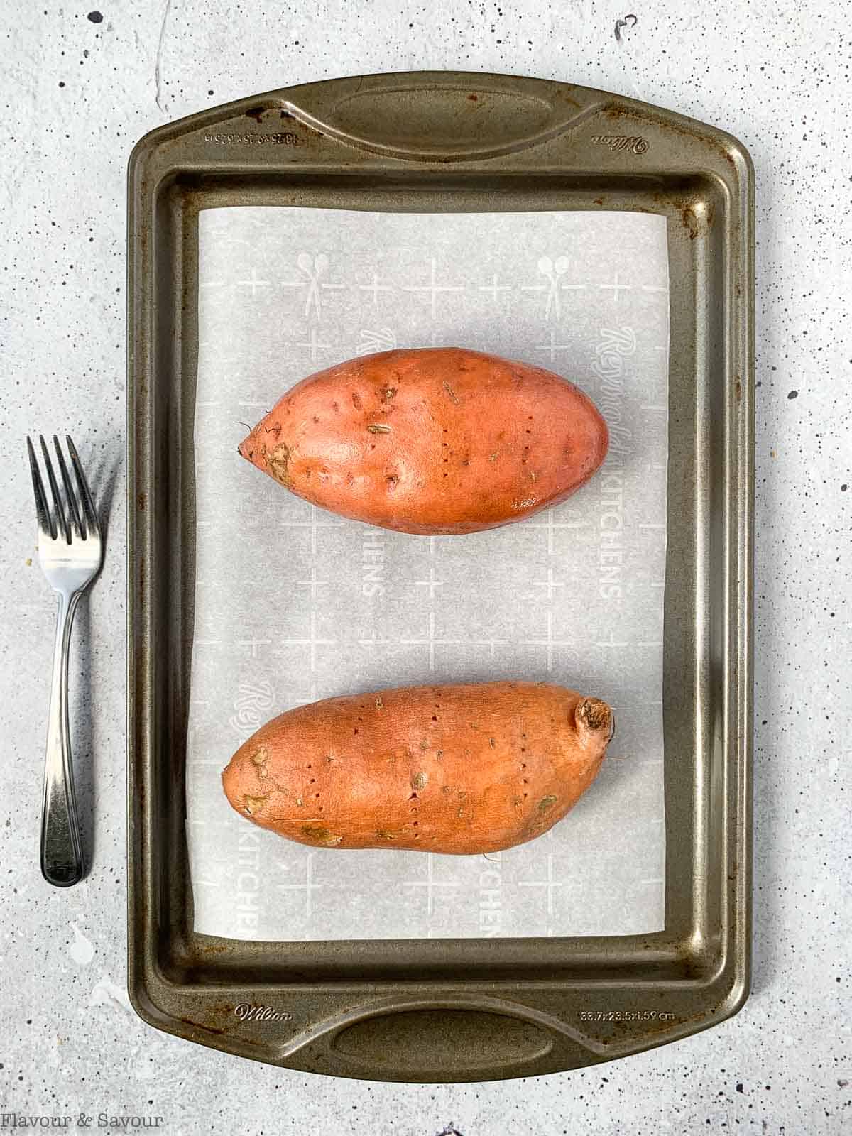 Two sweet potatoes on a baking sheet.
