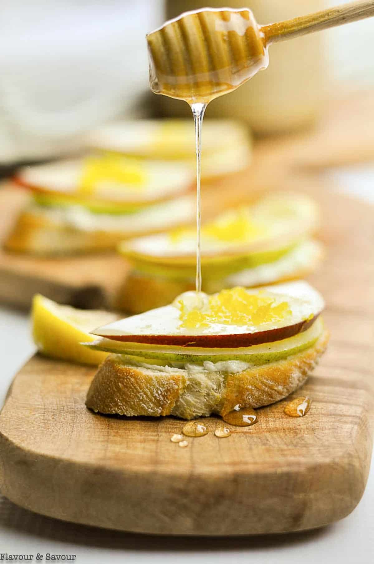 Drizzling honey on blue cheese and pear crostini