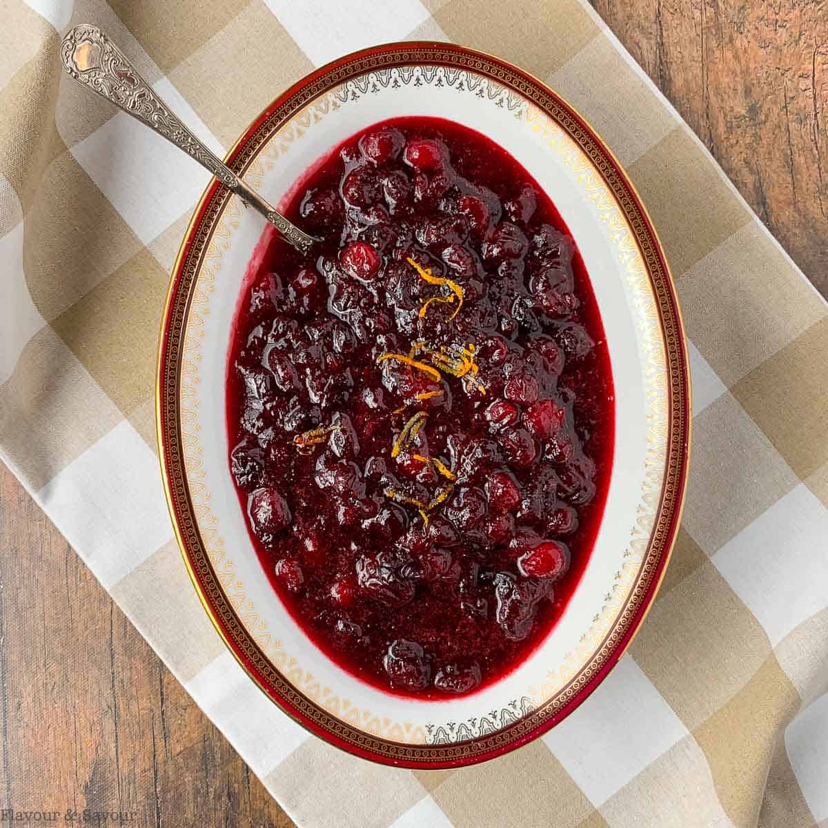 an oval bowl of fresh cranberry orange sauce with cinnamon and cloves