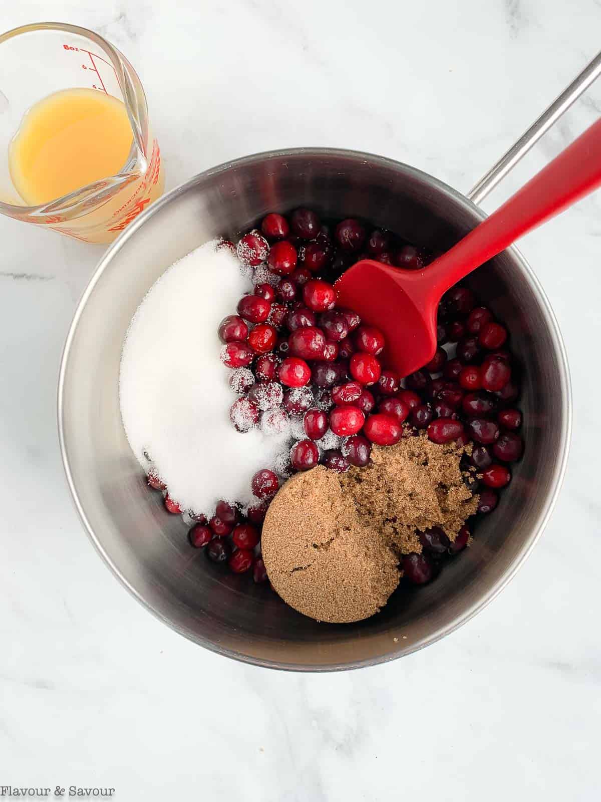 Combining ingredients for cranberry orange sauce in a saucepan.