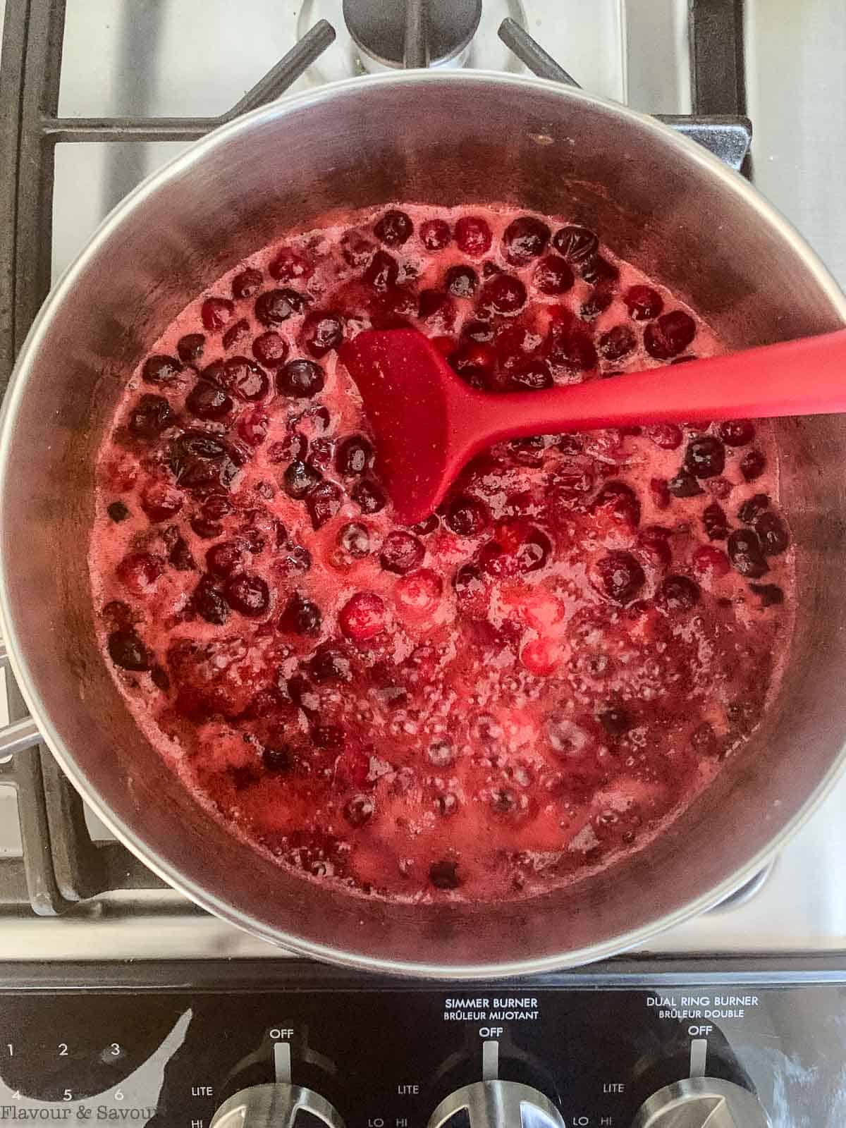 Cranberry sauce boiling in a saucepan.