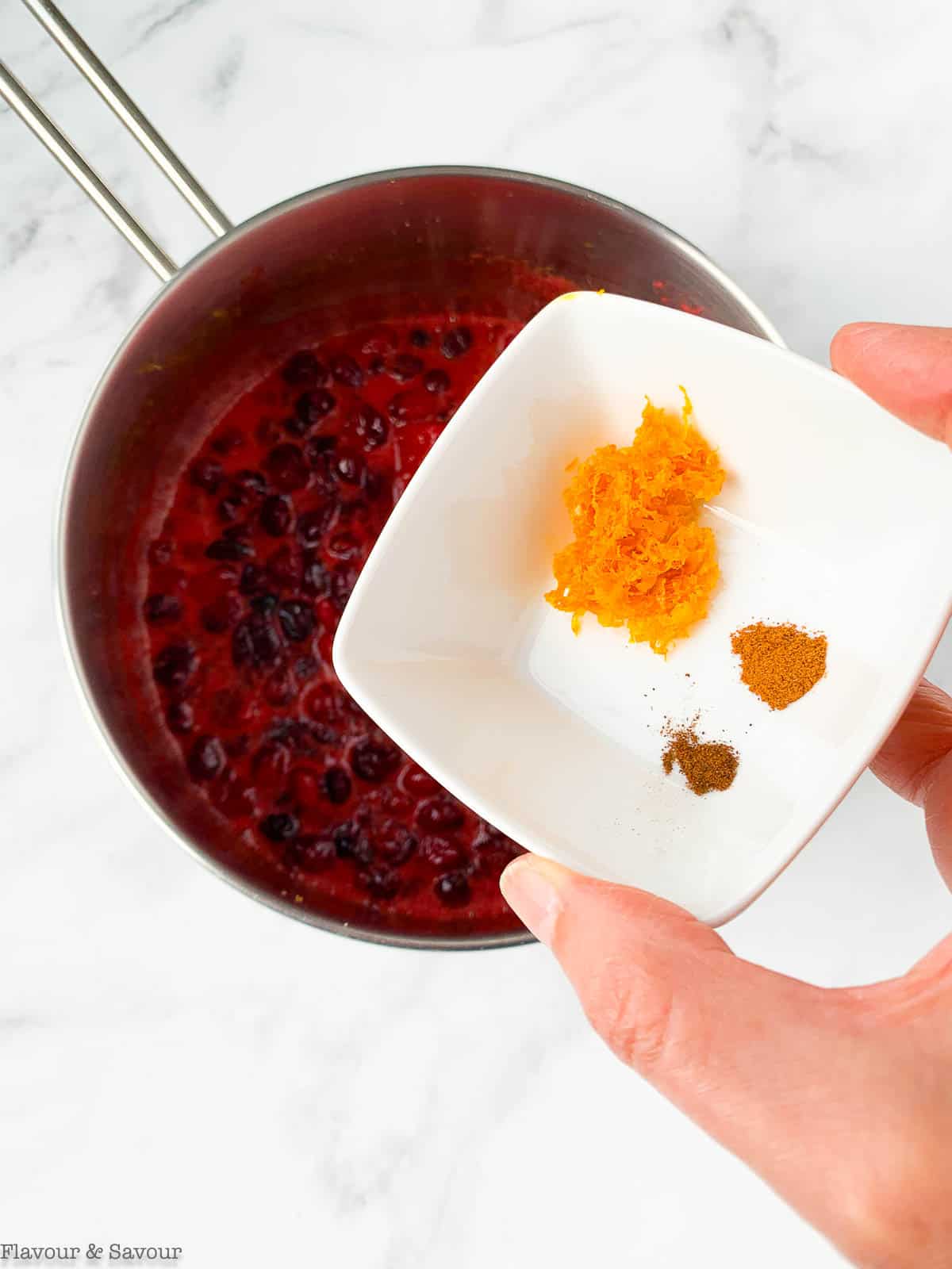 Adding orange zest and spices to cranberry sauce.