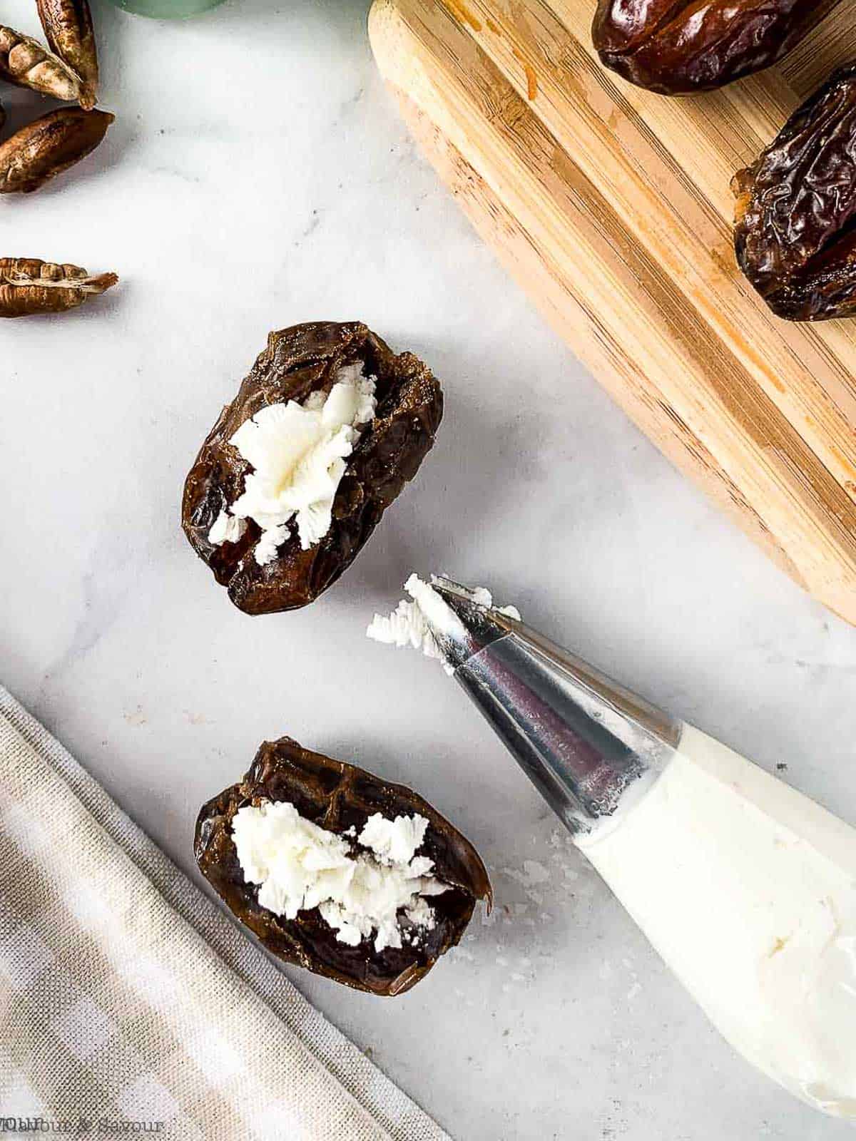 Filling Medjool dates with goat cheese using a piping bag.