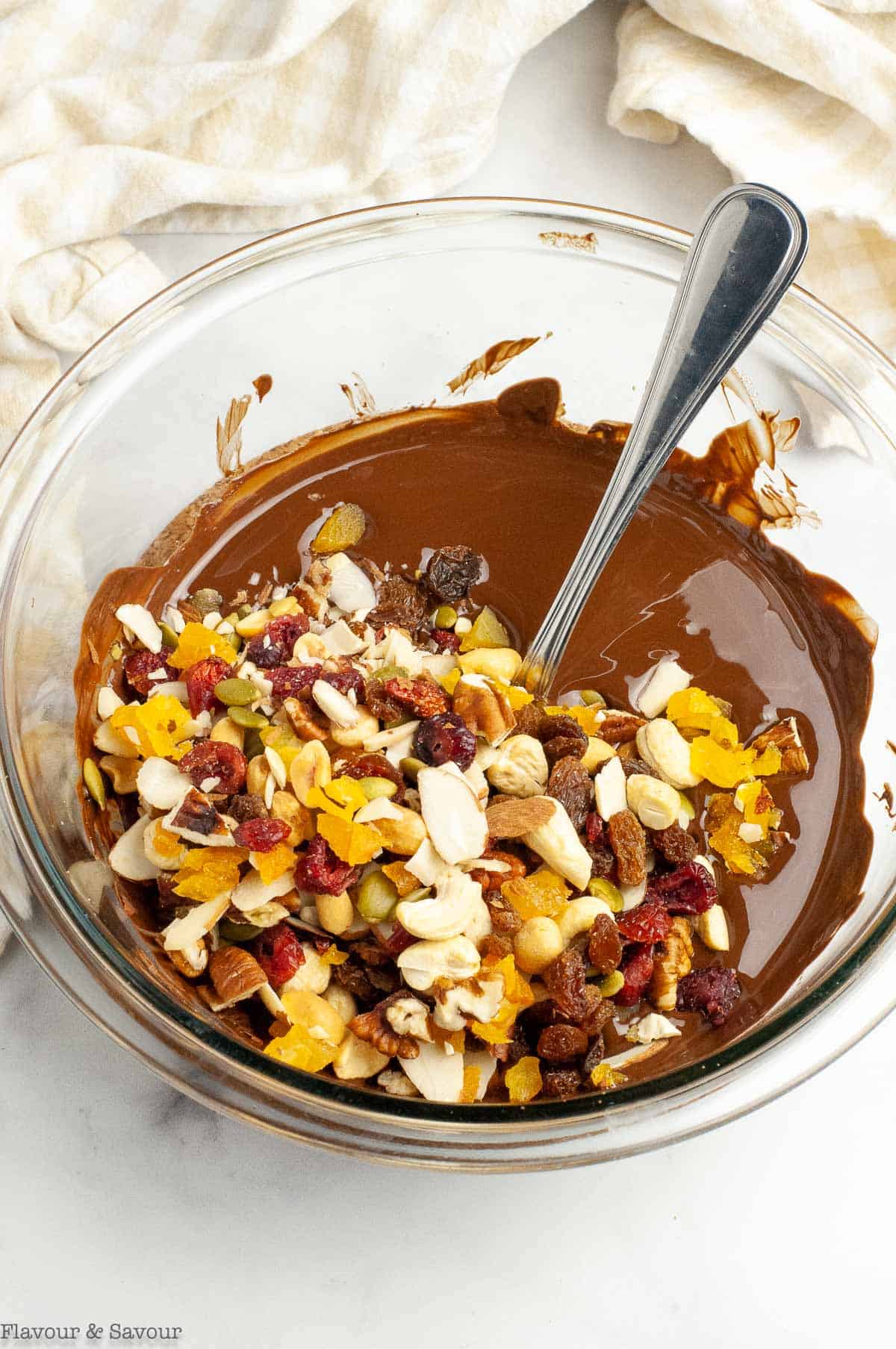 Nuts and dried fruit in a bowl of melted chocolate.